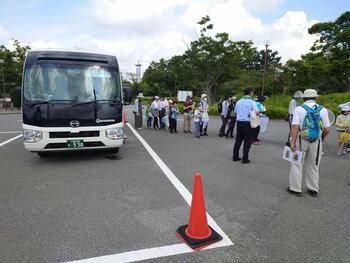 総合公園駐車場でバスから降りてくるツアー参加者の写真